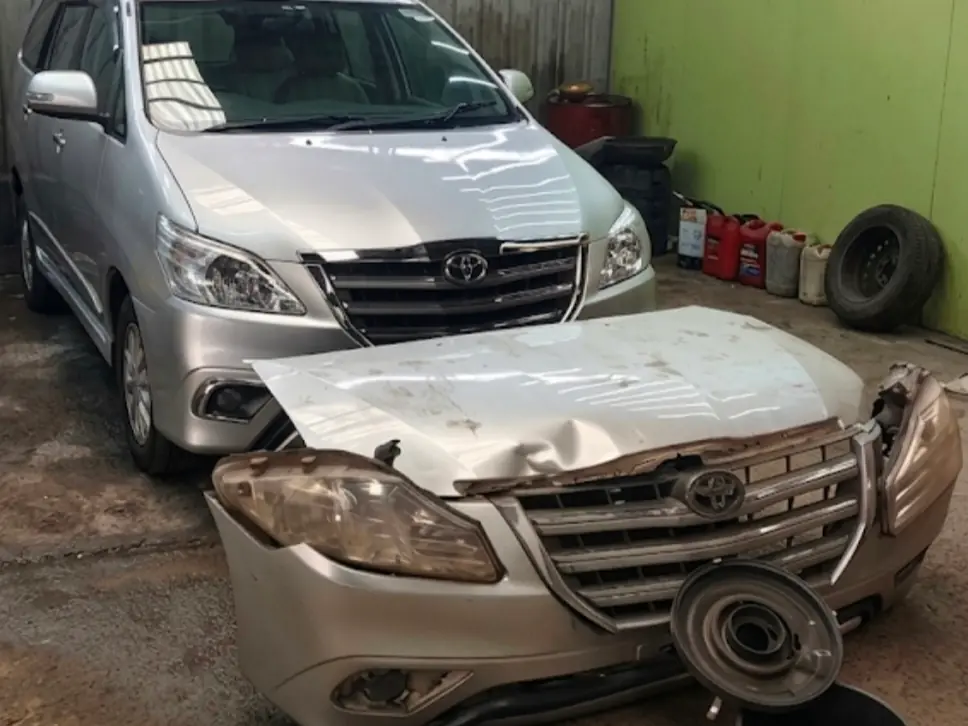 Accident-damaged Toyota Innova with its front crushed, in the workshop for repair