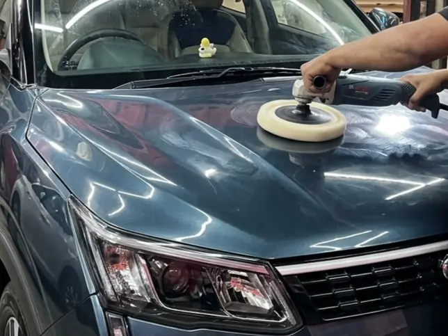 Machine polishing the bonnet of a grey Mahindra SUV
