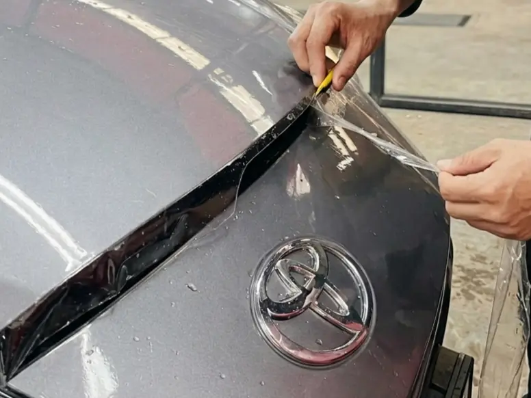 Paint protection film being trimmed on a car's bonnet