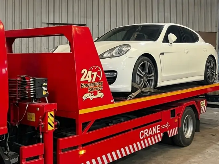 Porsche Panamera loaded on a red flatbed recovery truck at the workshop